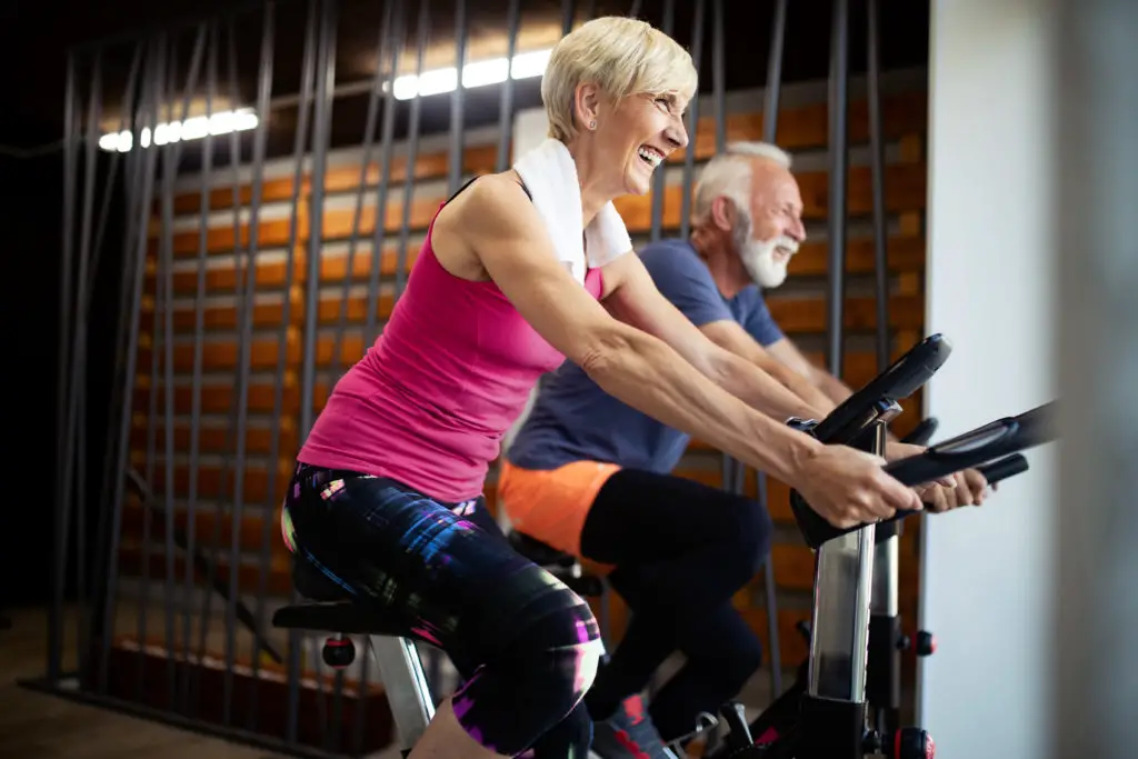  Pareja de personas mayores en bicicletas estáticas