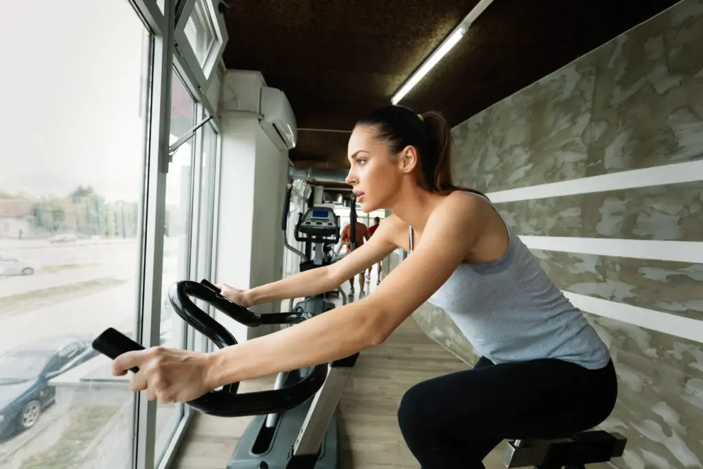 Giovane donna che fa ciclismo indoor